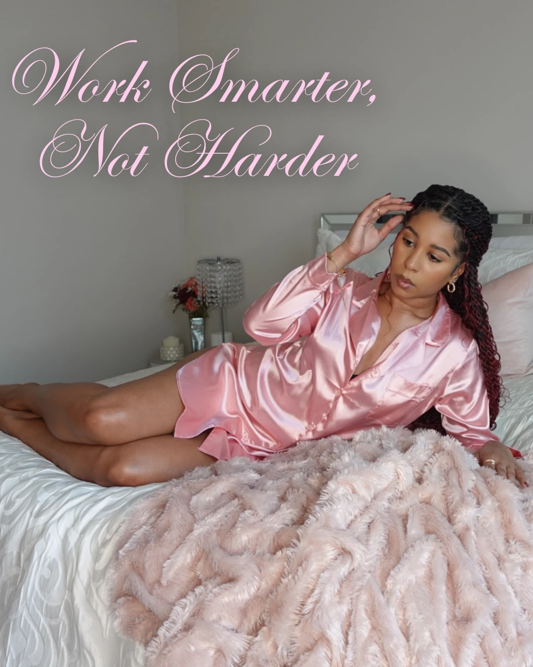 Indya lounging on her bed in pink satin under the words Work Smarter, Not Harder